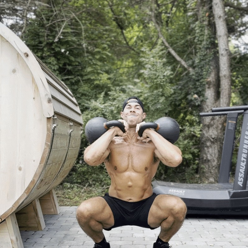 Athletic man performing a kettlebell squat outside